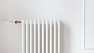 Wide open plan of new metal radiator of the central heating system installing on white copy space wall in modern apartment.